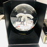 THERE'S A NO. 5 MINIATURE CHANEL PERFUME IN THE GLOBE ALONG WITH SIGNATURE WHITE BAGS, AND GORGEOUS CAMELLIAS ON THE BOTTOM.